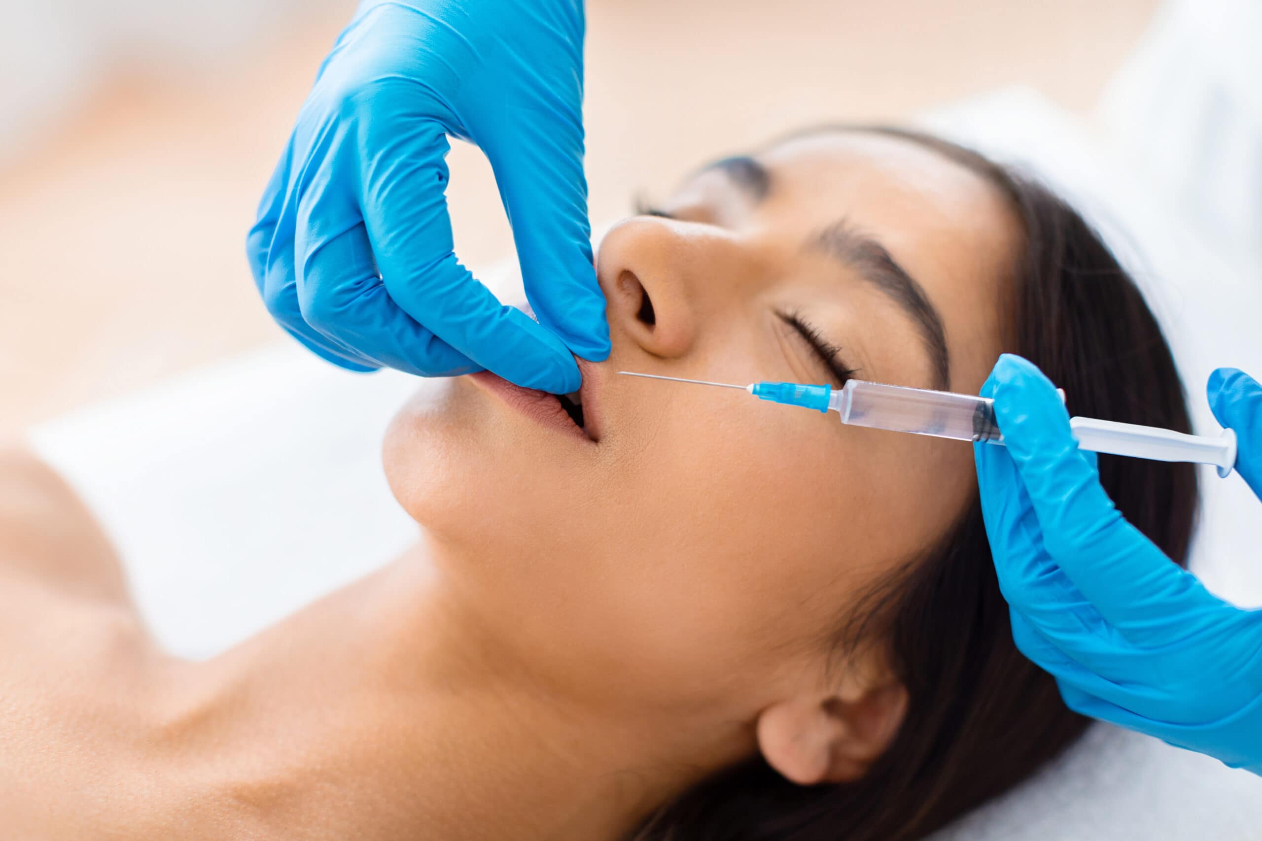 A medical professional after the Level 7 diploma from Acquisition Aesthetics, injects the lips of young Indian woman